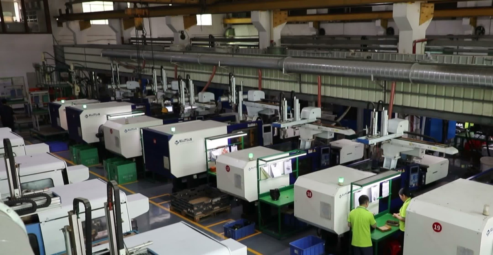 Rows of injection molding machines with operators on the Fudakin factory floor
